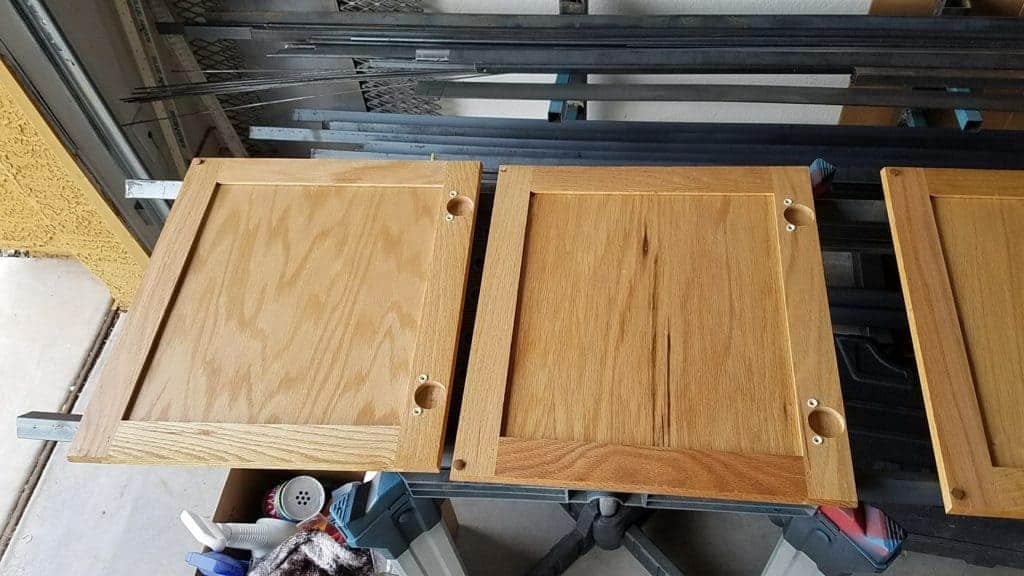 Hubby placed long pieces of steel across 2 tables to hold the cabinet doors in place for staining.